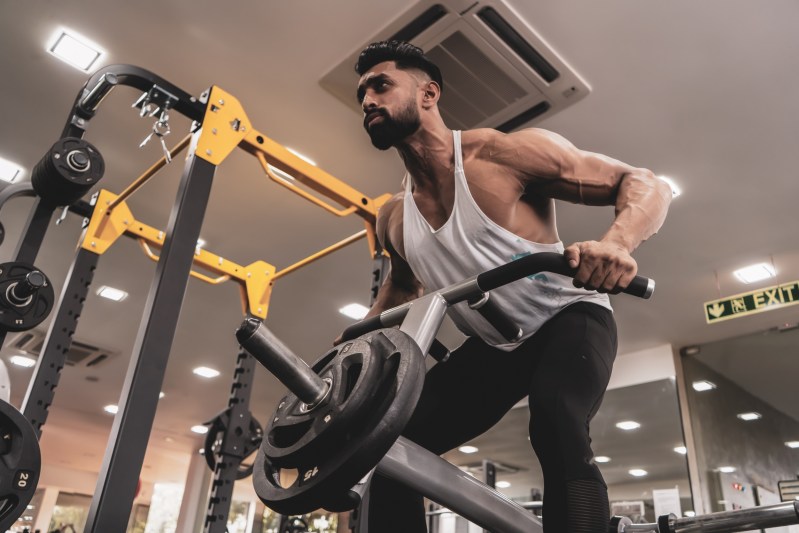 Guy in gym using machine to do the T-bar row exercise